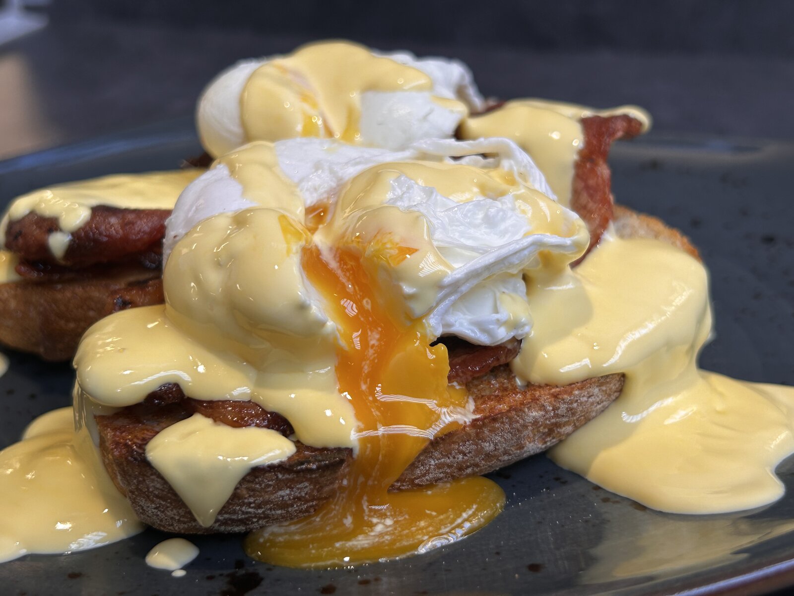 Eggs Benedict on toasted sourdough with bacon and hollandaise.